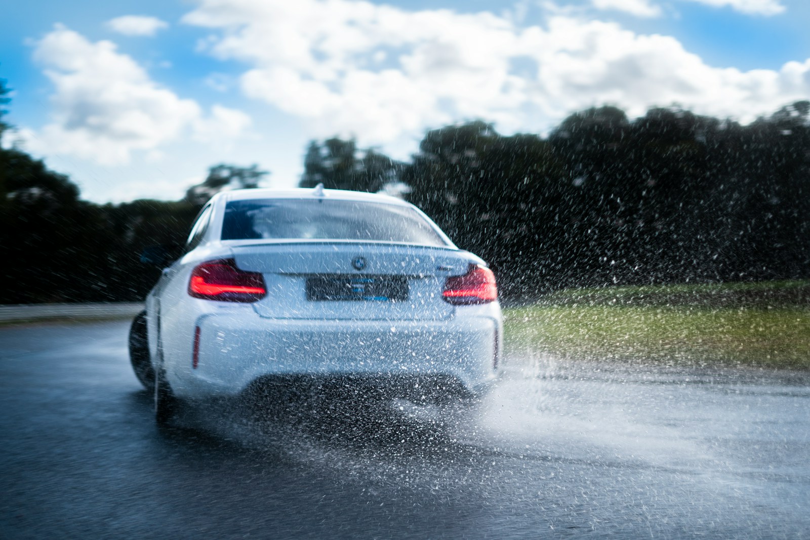 a white car driving down a wet road